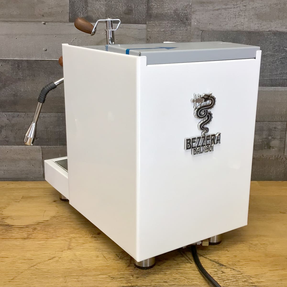 A RETURNED & REFURBISHED Bezzera Aria HX Special Edition Espresso Machine w/ Flow Control (C104) with a steam wand and wooden handles sits on a wooden countertop against a gray wall—ideal for flow control espresso fans. © 2025 1st-line.com