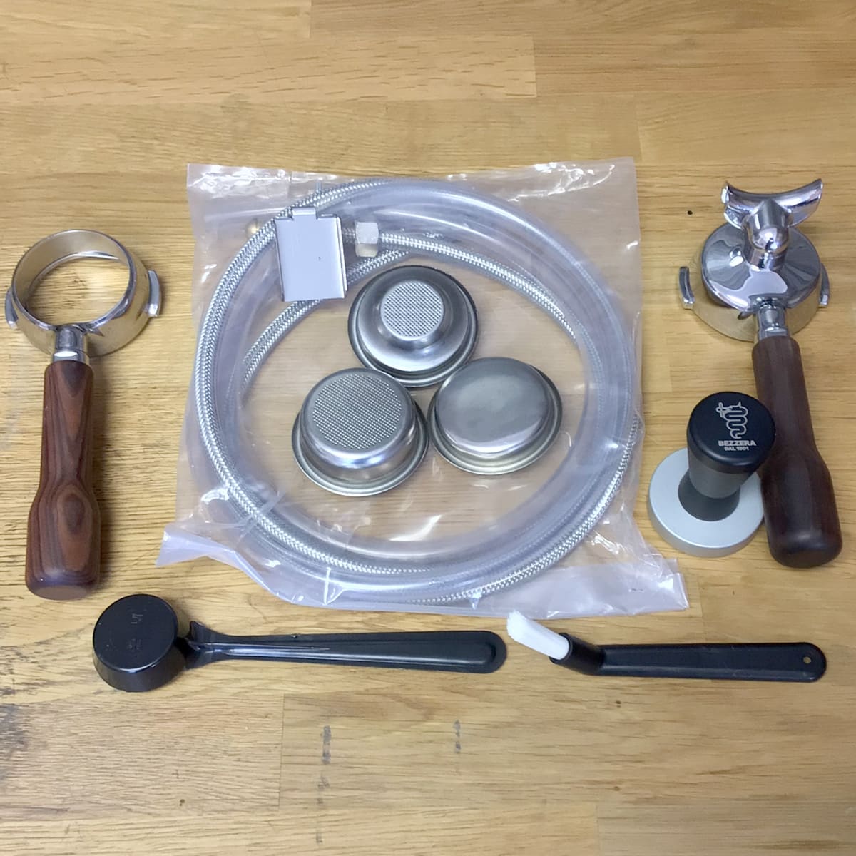 Assorted espresso accessories—portafilters, baskets, tamper, dosing tool, and brush—perfect for maintaining your RETURNED & REFURBISHED Bezzera Aria HX Special Edition Espresso Machine with Flow Control (C104). © 2025 1st-line.com
