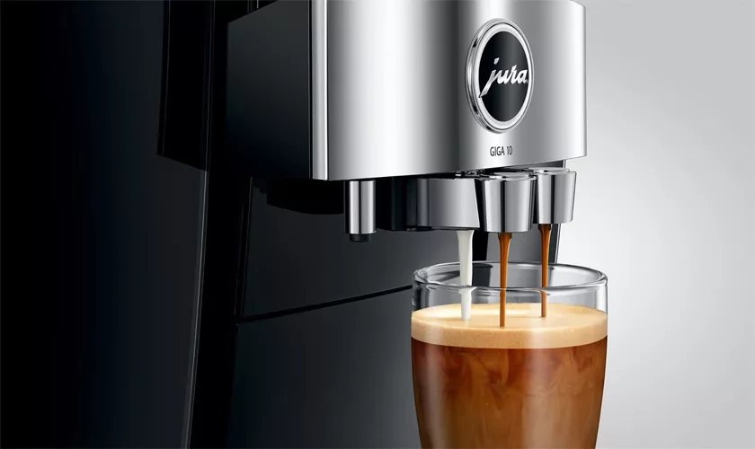 A close-up of the Jura GIGA 10 Super-Automatic Espresso Machine dispensing espresso into a clear glass, highlighting its rich crema and showcasing the machine’s modern design with chrome accents. © 2025 1st-line.com