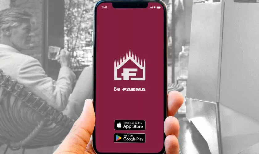 A hand holds a smartphone showing the Be Faema app on a maroon screen, with App Store and Google Play buttons. In the grayscale café background, people gather around a Faema Faemina Dual Boiler Espresso Machine. © 2025 1st-line.com