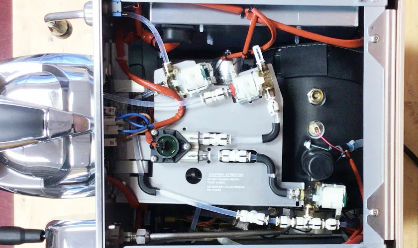 An overhead view of the Faema Faemina Dual Boiler Espresso Machine’s internal components displays neatly arranged wires, tubes, circuit boards, and metallic parts inside the machine’s housing. © 2025 1st-line.com