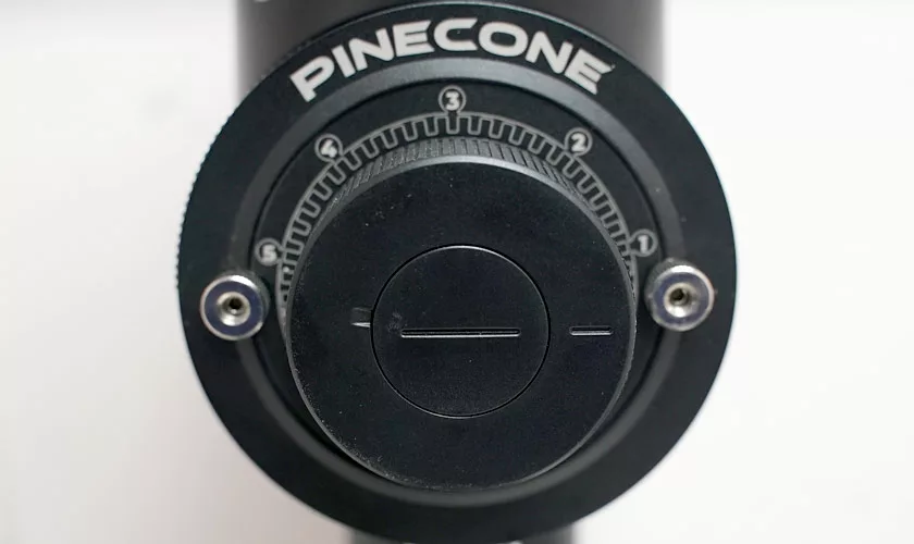 Close-up of a black dial labeled PINECONE, part of the Pinecone Pinion All-Purpose Espresso Coffee Grinder, showing numbered settings 0–3 and two screws against a white background. © 2025 1st-line.com