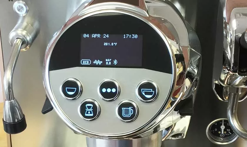 Close-up of the Faema Faemina Dual Boiler Espresso Machine control panel showing date, time, and temperature, with illuminated coffee option buttons and a steam wand visible on the left. © 2025 1st-line.com