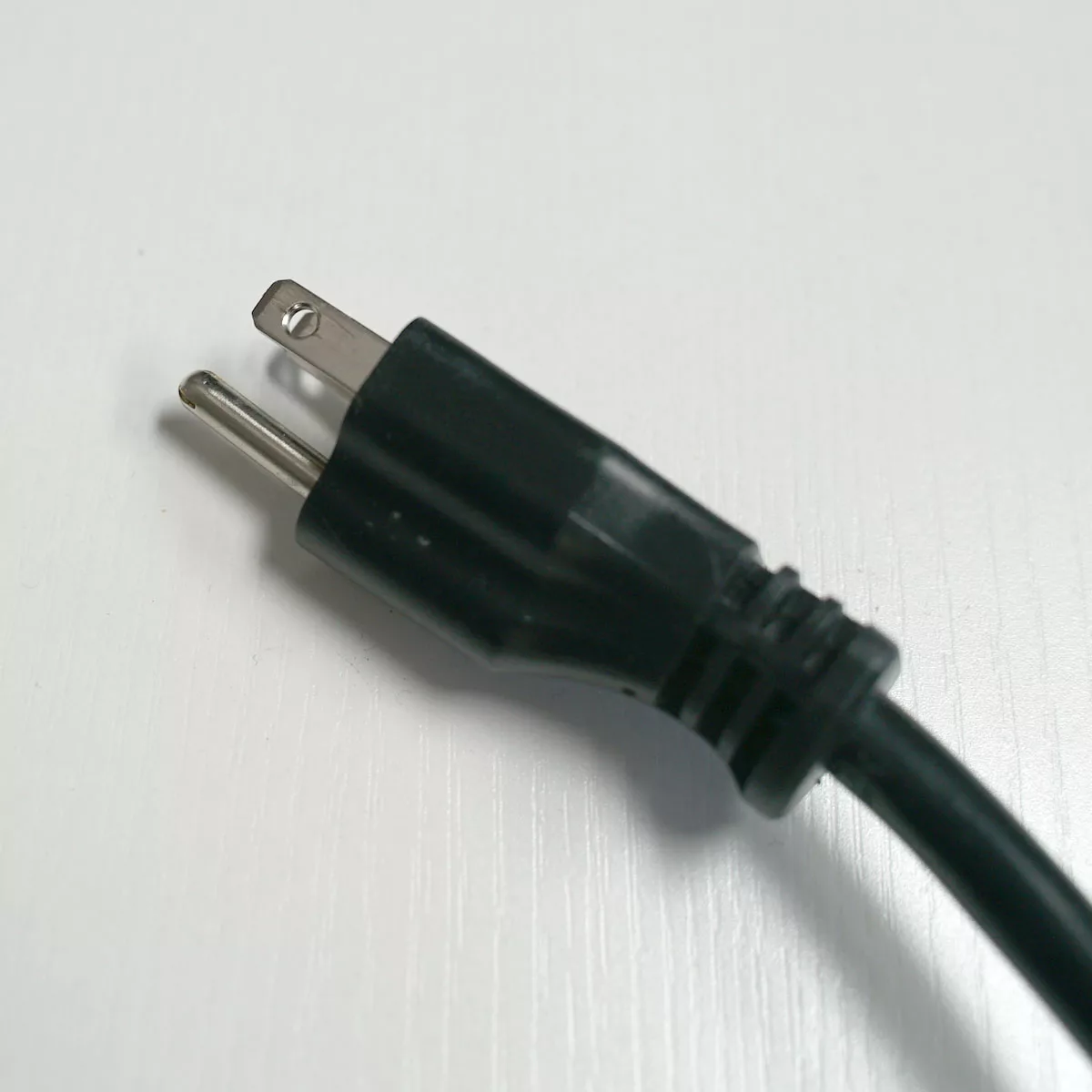 A close-up of a black, two-prong electrical plug lying on a white surface, often used to power appliances like the VBM Domobar Super espresso machine or other analogic devices. © 2025 1st-line.com