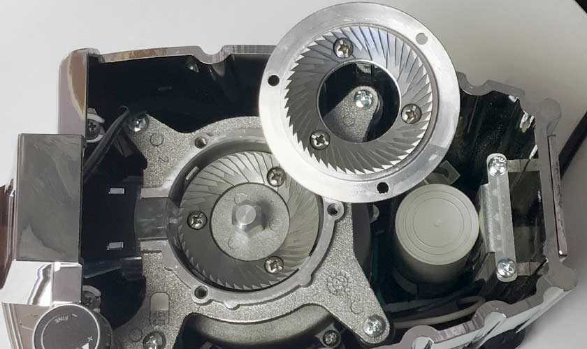 Close-up of the Faema TOUCH & MATCH Espresso Coffee Grinder interior, highlighting exposed burr grinding mechanisms, metal gears, and a small white plastic component—key features of its innovative design. © 2025 1st-line.com