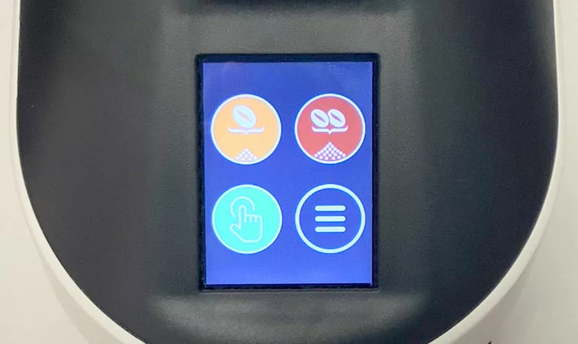 Close-up of the Quamar Nemo QE Espresso Coffee Grinders touchscreen, showing four circular icons: orange and red plant symbols, a light blue fingerprint, and white horizontal lines on blue. © 2025 1st-line.com