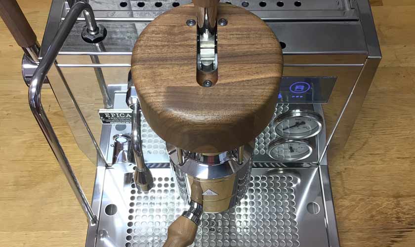 Overhead view of the Rocket Epica Espresso Machine in stainless steel with wood accents, featuring a portafilter, pressure gauges, steam wand, and tamping area on a metal drip tray set on a wooden countertop. © 2025 1st-line.com
