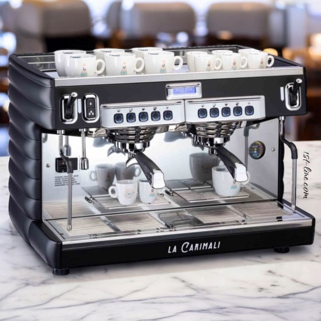 A Carimali Bubble 2 Group Commercial Espresso Machine (120V or 230V available) sits on a marble countertop with white cups on top, set against a blurred café background with tables and chairs, creating an inviting scene. © 2025 1st-line.com