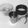 A set of coffee brewing accessories—glass funnel, stainless steel cup, black silicone ring, and metal filter holder—perfect for use with the Eureka Mignon Single Dose Kit, all neatly arranged on a white surface. © 2025 1st-line.com