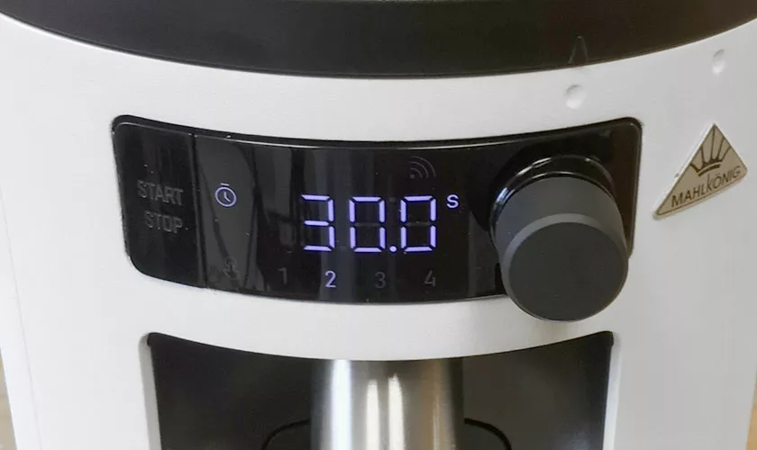 Close-up of the digital control panel on a white Mahlkonig X54 Allround Home Grinder, showing 30.0 s in blue numerals, with a large black knob to the right and a START/STOP button on the left. © 2025 1st-line.com