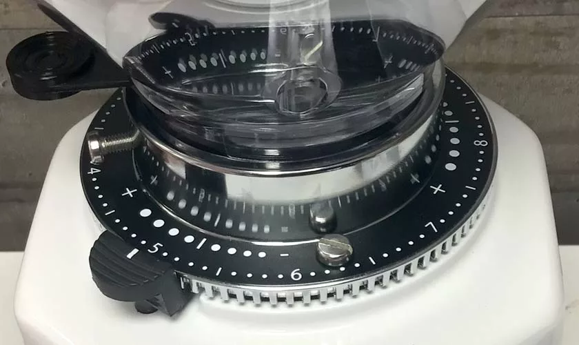 Close-up of the Quamar M80TP Espresso Coffee Grinders numbered adjustment dial, featuring a transparent hopper above and a black adjustment knob on its white base. © 2025 1st-line.com