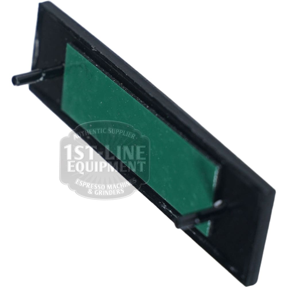 Rectangular black and green plastic component with two cylindrical pins, designed as a replacement part for the Torre TARG0001 Peppina Name Plate espresso machine or grinder. © 2025 1st-line.com