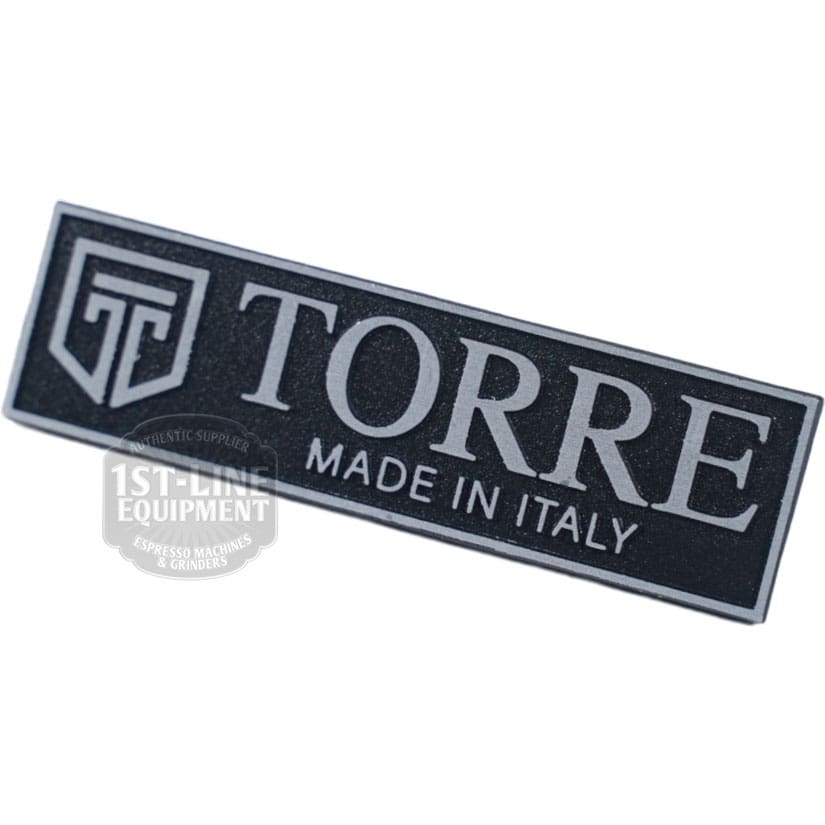 Torre TARG0001 Peppina Name Plate: A rectangular black and silver plate featuring TORRE MADE IN ITALY beside a geometric logo, with a 1st-Line Equipment Espresso Machines & Grinders watermark. © 2025 1st-line.com
