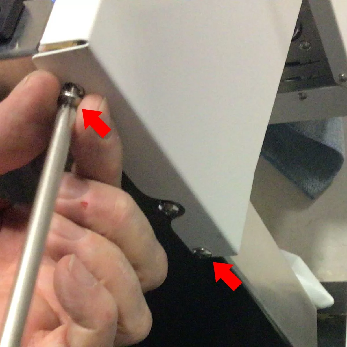 A hand uses a screwdriver to tighten a screw on a white Bellezza Bellona side panel, with two red arrows pointing at screws being fastened. © 2025 1st-line.com