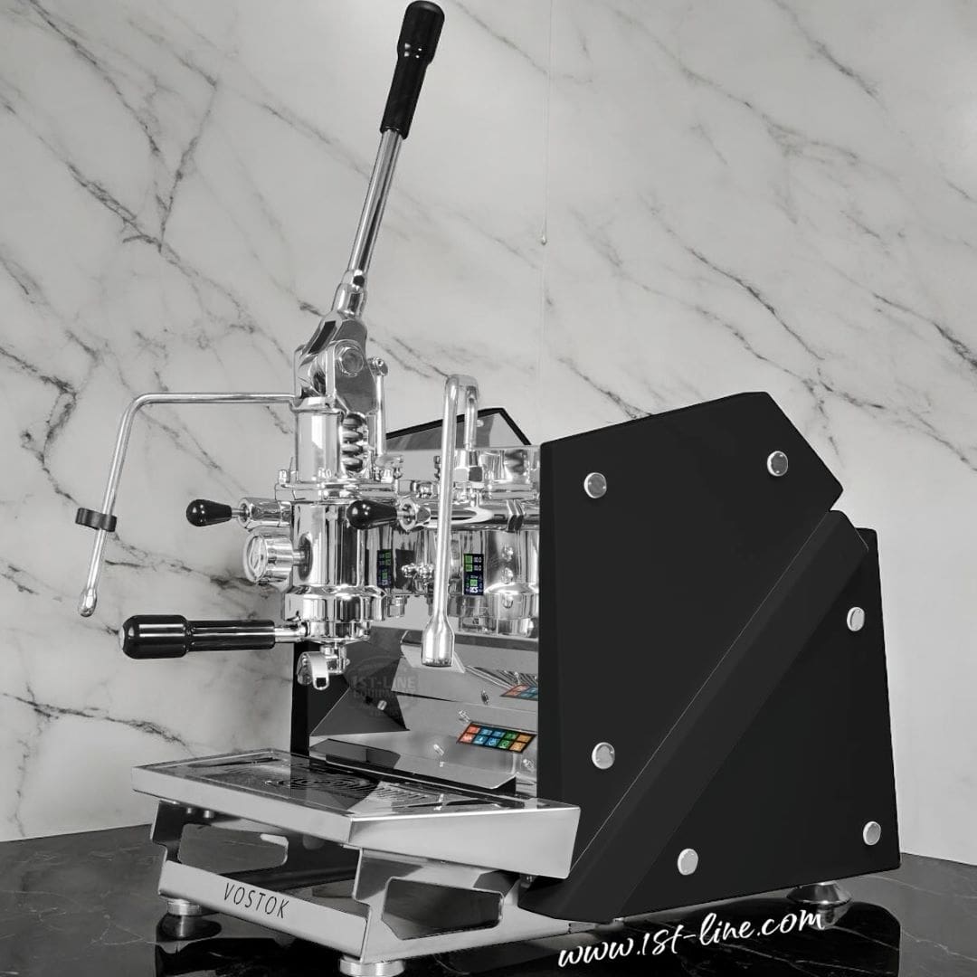 The ACS Vostok Lever Espresso Machine, featuring black side panels, chrome accents, dual levers, and a digital display with colorful buttons, sits on a marble countertop for a modern and polished look. © 2025 1st-line.com