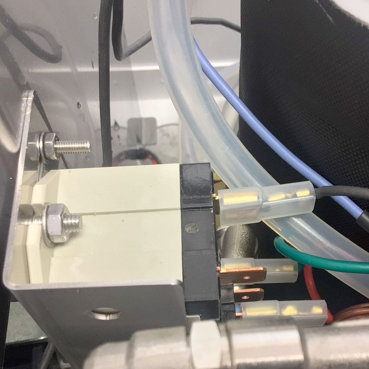 Close-up of an electrical component with multiple wires, metal bolts, and a transparent tube inside the Nurri R-Type SB (HX) Espresso Machine. The background features part of the larger HX system within this high-performance machine. © 2025 1st-line.com