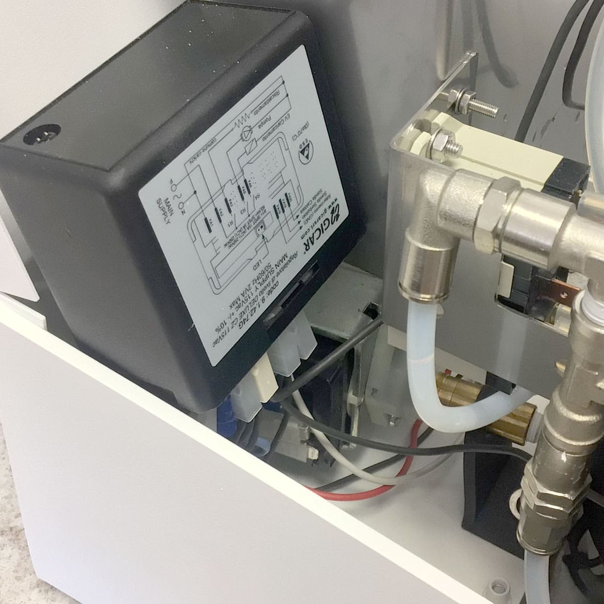Close-up of the Nurri R-Type SB (HX) Espresso Machine’s internals, displaying HX wiring, a black control box with diagram, transparent tubes, metal connectors, and electronic fittings. © 2025 1st-line.com