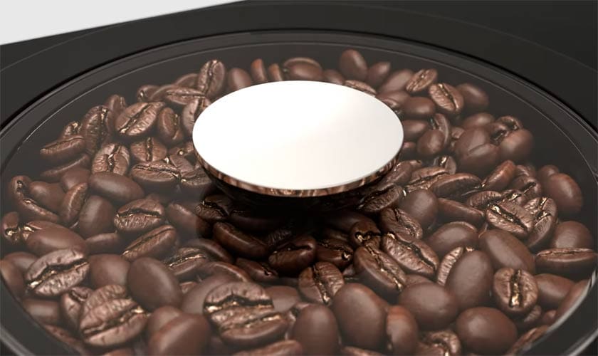 Glossy roasted coffee beans sit under a glass lid with a metallic knob, ready to be brewed in the Jura ENA 4 Super-Automatic Espresso Machine. © 2025 1st-line.com