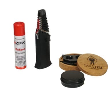 The Java Jim Espresso Smoker Kit includes a black cigar torch lighter, a can of Zippo butane fuel, a cigar cutter, and premium accessories inside an open wooden box labeled Espresso Smoker Kit. © 2025 1st-line.com