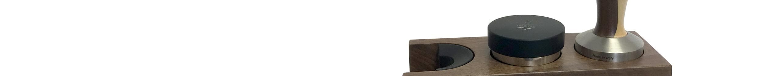 A close-up of an ACC TST kit wooden coffee tamper holder, displaying a black coffee tamper and a metallic tamper, with one empty slot visible. The background is white. © 2025 1st-line.com