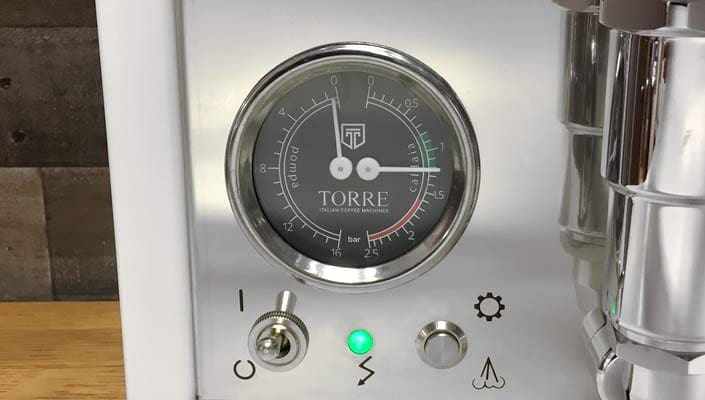 Close-up of the Torre Alfredo TSP HX Espresso Machine gauge displaying bar pressure, metallic switch, green indicator light, and control icons—showcasing the precision engineering of this espresso machine. © 2025 1st-line.com