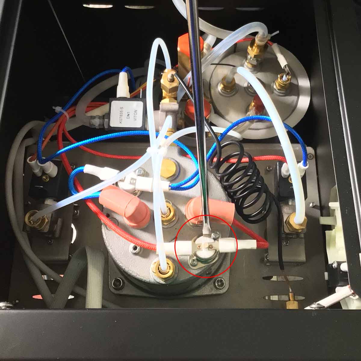 Interior view of a machine showing multiple tubes, wires, connectors, valves, and metal components arranged in a compact, organized manner, possibly part of a scientific or industrial device. © 2025 1st-line.com