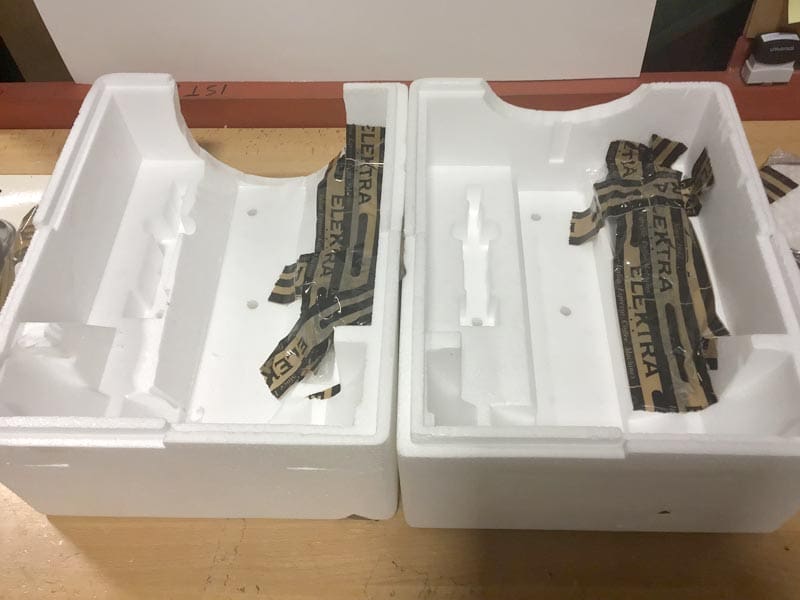Two white styrofoam packaging inserts are displayed side by side on a table, each with black and gold ELEKTRA tape partially stuck inside the molded cavities, suggesting repackaging of the Elektra Semi-Automatica. © 2025 1st-line.com