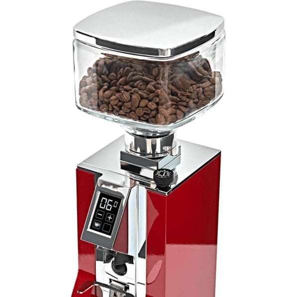 A red Eureka electric coffee grinder with shiny silver accents, topped with a Eureka ACC-CMV-001-1KIT Mignon Glass Bean Hopper filled with coffee beans and a digital display. © 2025 1st-line.com