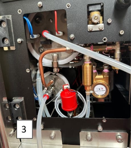 Close-up view of machinery with various tubes, pipes, a pressure gauge, and a red-capped valve—features seen in ACS Vesuvius systems. The number 3 is displayed in a white box at the bottom left corner. © 2025 1st-line.com