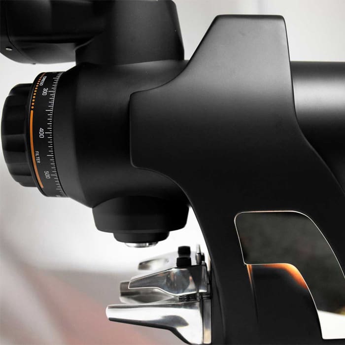 A close-up of a stylish espresso machine highlights its metallic portafilter and black dial with measurement marks—ideally matched with the Quamar Sirio-Q Espresso Coffee Grinder for ultimate precision. © 2025 1st-line.com