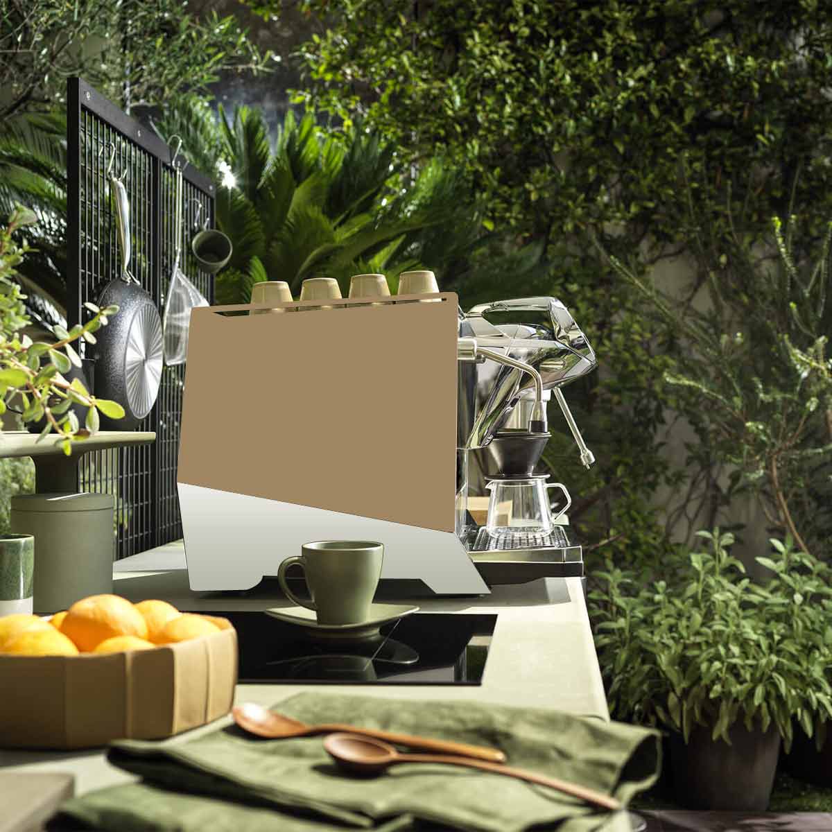 A Faema Faemina Dual Boiler Espresso Machine with AUTOSTEAM sits on an outdoor counter, topped with cups and surrounded by green plants, a bowl of oranges, kitchen utensils, and a cup and saucer under natural sunlight. © 2025 1st-line.com