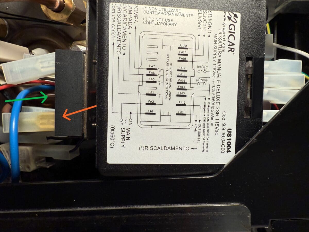 Close-up of an ECM Espresso Machine control box with a wiring diagram label. Colored wires (blue, green/yellow) are visible, and an orange arrow points toward a white connector—helpful for coffee machine troubleshooting. © 2025 1st-line.com