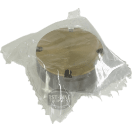 A component of the ACS Safety System—a round, metallic object with visible screws on its gold and silver top—is sealed in a clear plastic bag and displayed against a plain black background. © 2025 1st-line.com