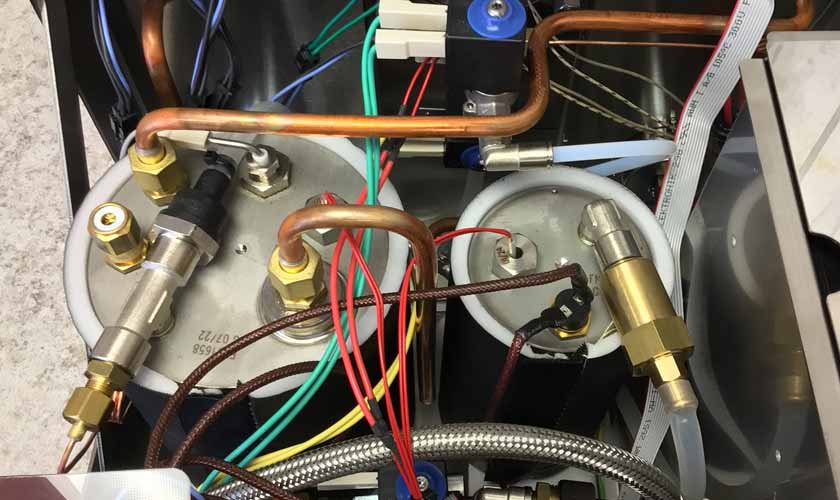 Close-up of internal components in the Nurri L-Type Lever Leva Dual Boiler Espresso Machine, featuring metal cylinders, copper pipes, brass valves, wires, and tubes in a compact dual boiler layout. © 2025 1st-line.com