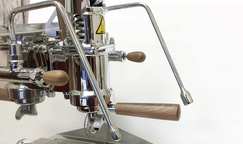 Close-up of the Nurri L-Type Lever Leva Dual Boiler Espresso Machine, featuring chrome finish, wooden handles, an L-Type lever, and a caution symbol, set against a plain white background. © 2025 1st-line.com
