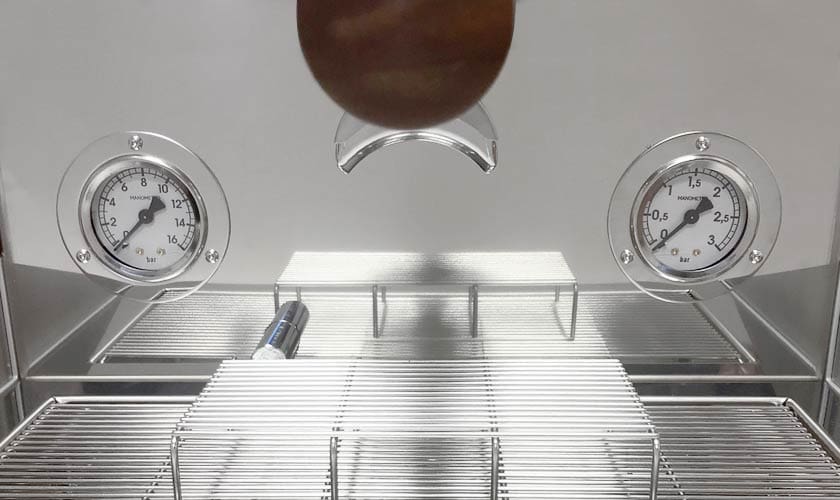 Close-up of two round pressure gauges on a shiny metal surface with wire racks and a cylinder below—showcasing the precision interior of the Nurri L-Type Lever Leva Dual Boiler Espresso Machine. © 2025 1st-line.com