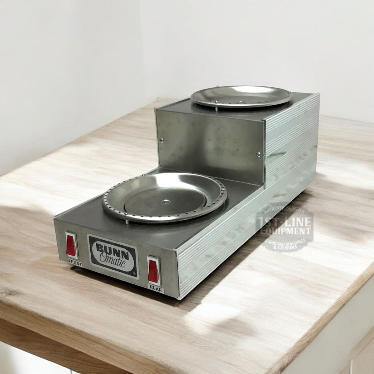 The SIDEWALK SALE - Bunn Dual Warmer (E109) features two heated plates, front and top, with labeled power switches for each. Ideal for your next sidewalk sale, it sits stylishly on any wooden surface in a bright room. © 2025 1st-line.com