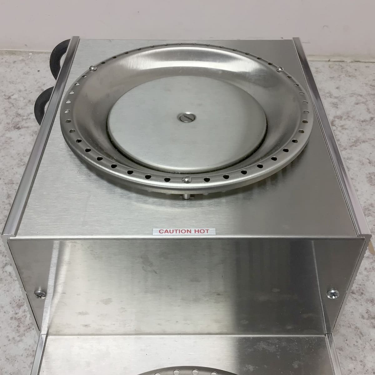 The SIDEWALK SALE - Bunn Dual Warmer (E109), with a stainless steel, lidded round container and CAUTION HOT label, sits on a speckled countertop—ideal for your next sidewalk sale event. © 2025 1st-line.com