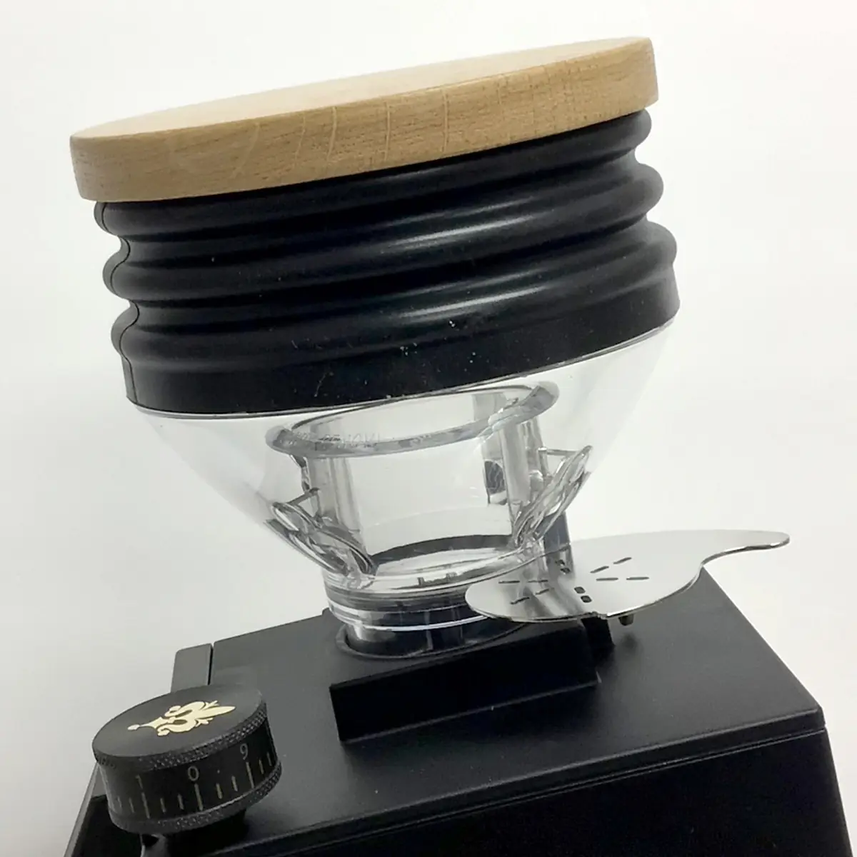 A close-up of the Eureka Mignon Single Dose Espresso Coffee Grinder shows its clear single dose hopper with a wooden lid, textured black collar, and a black adjustment dial with white markings on the base.