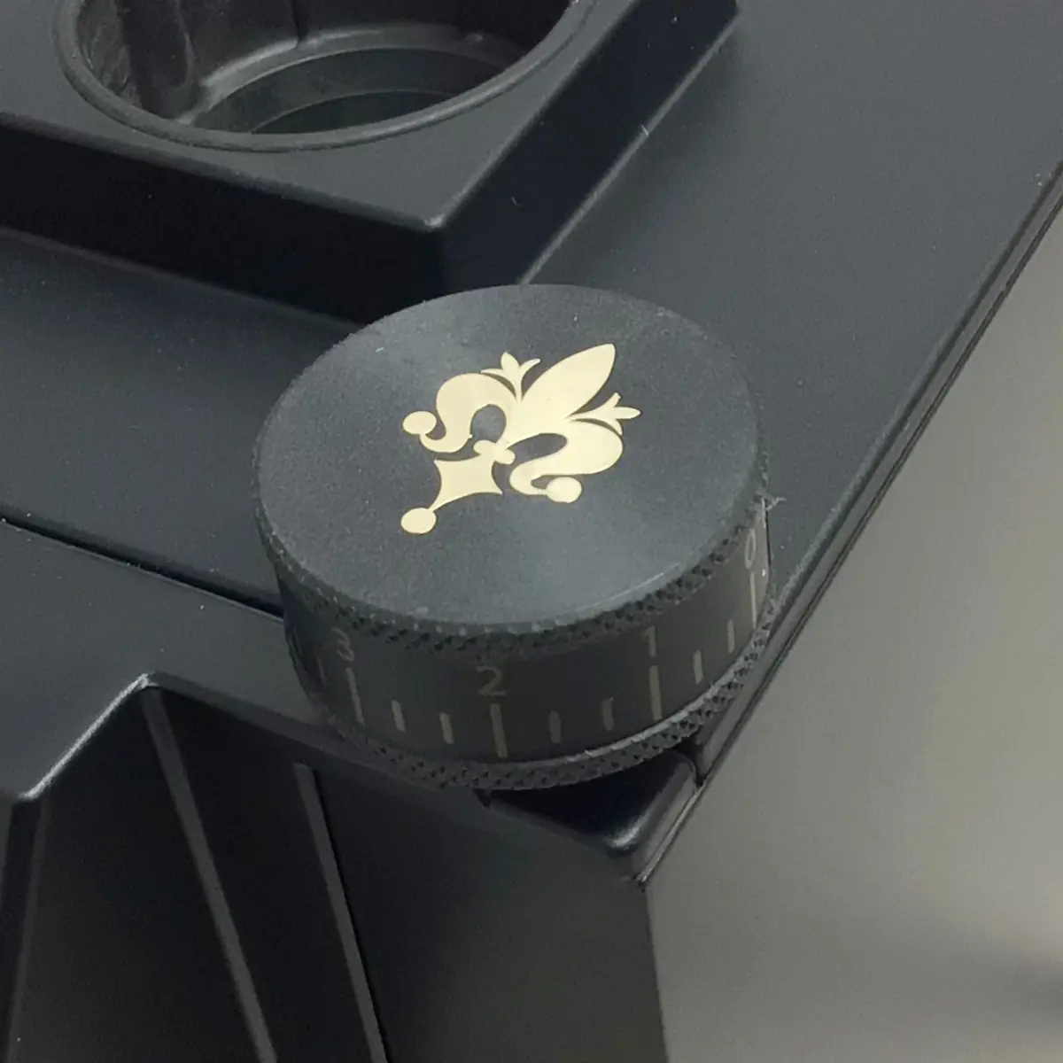 A close-up of the black dial with gold fleur-de-lis and engraved numbers on the Eureka Mignon Single Dose Espresso Coffee Grinder, designed for precise single dose adjustments.