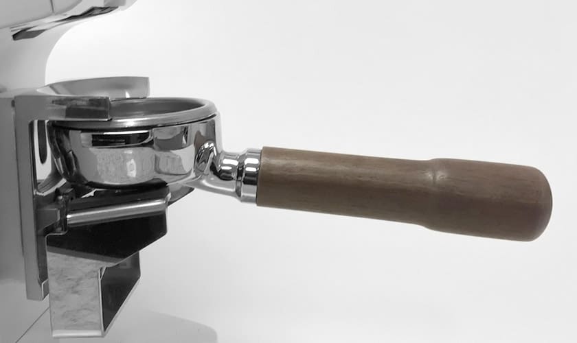 A close-up shows a portafilter with a wooden handle attached to an espresso machine, next to the Eureka Atom W 65 Weight Based Espresso Coffee Grinder, all set against a plain white background. © 2025 1st-line.com