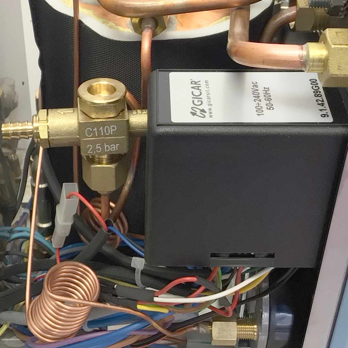 Close-up of plumbing and electrical parts inside the Torre Luigino HX Espresso Machine w/ Flow Control, including copper pipes, a brass C110P 2.5 bar valve, colored wires, and a black box with technical specs. © 2025 1st-line.com