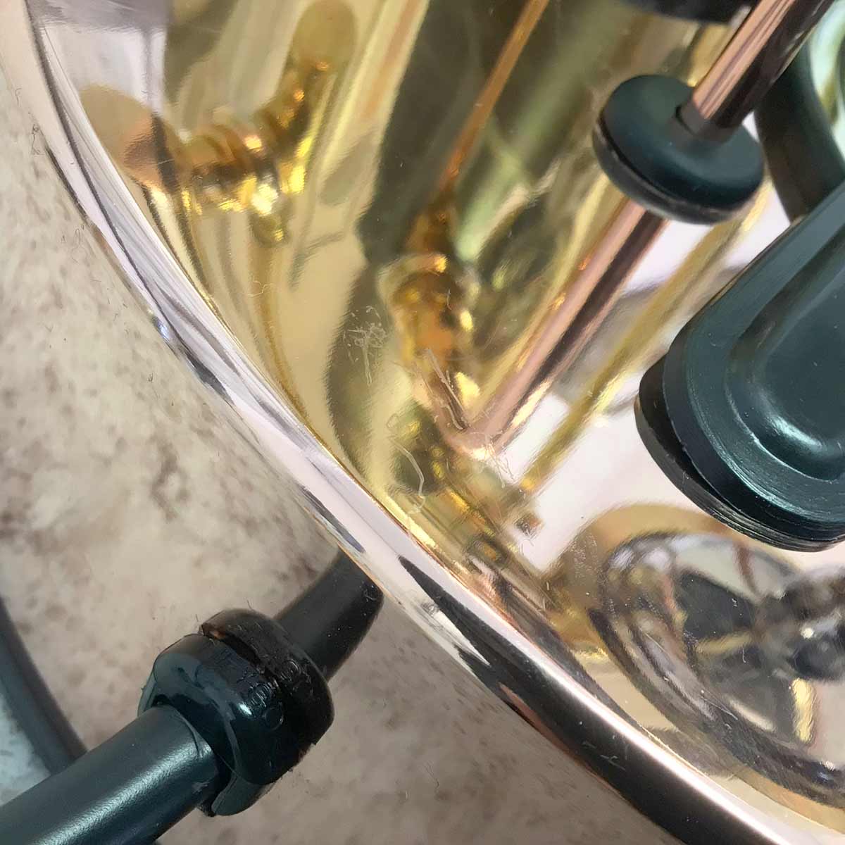 Close-up of the shiny brass surface on a SIDEWALK SALE - Elektra SX Microcasa Semiautomatica Espresso Machine RETURNED & REFURBISHED (E210), reflecting black cables and rubber fittings against a textured, light background. © 2025 1st-line.com