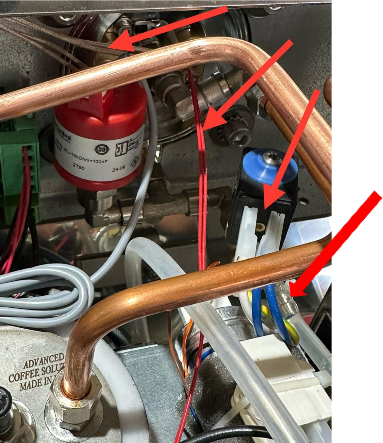 Close-up of the ACS Vostok's internal components, showing copper pipes, wires, connectors, and four red arrows highlighting different parts for identification or repair purposes.