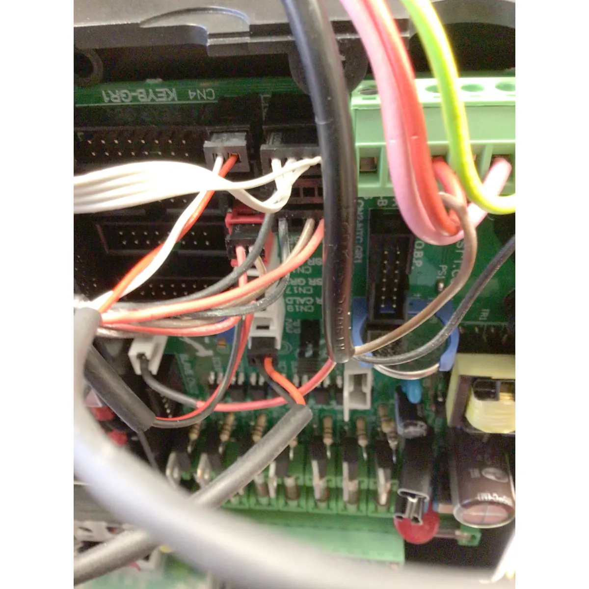 Close-up view of an electronic circuit board, like those in the Torre Peppina EVO Premium V2 Dual Boiler Espresso Machine w/ FC, featuring colored wires linked to capacitors, connectors, and chips.