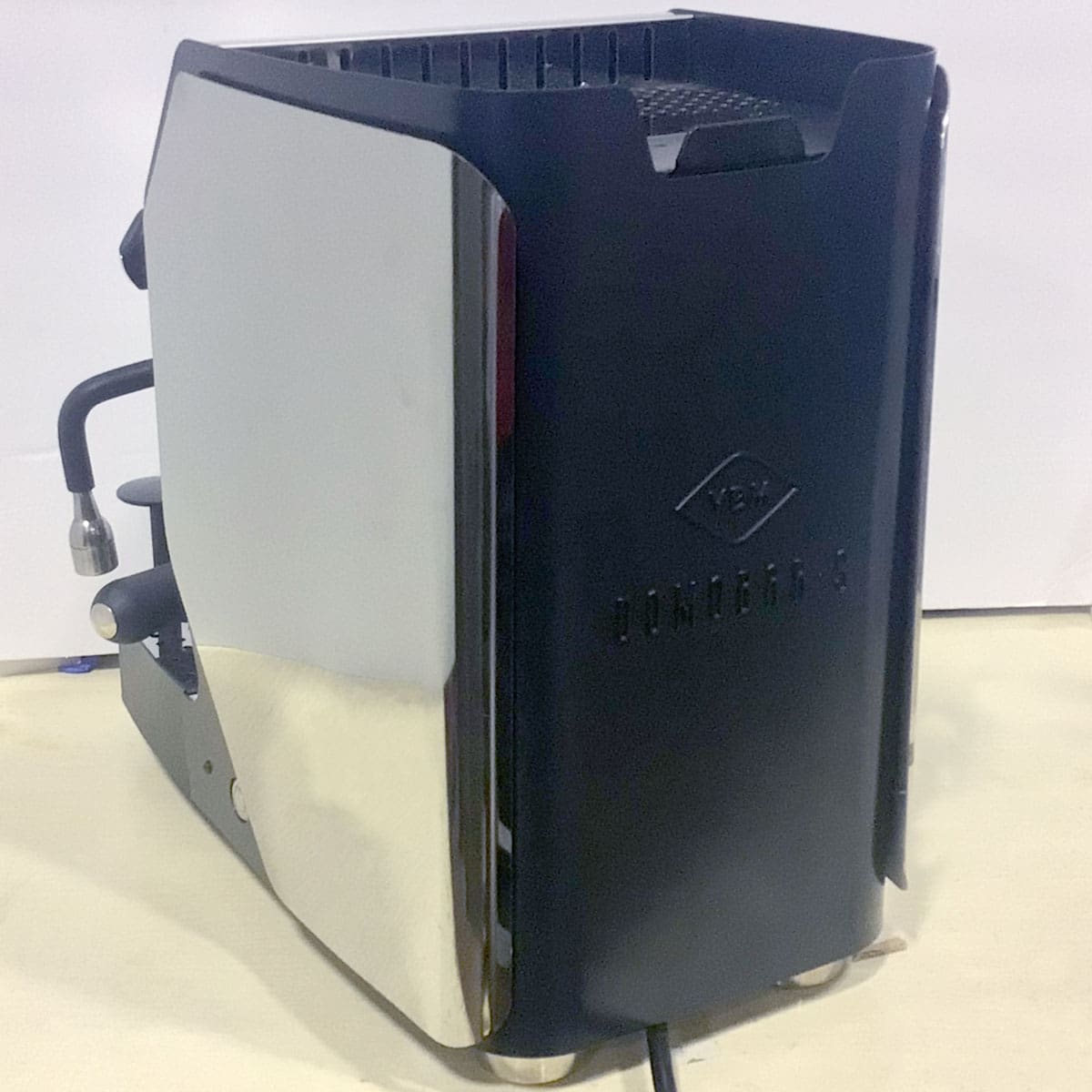 A SIDEWALK SALE - VBM Super Digital DUAL PROFILER Dual Boiler Espresso Machine (used, E111) with a stainless steel side panel and black matte finish sits on a light countertop, showing its steam wand and control knobs. © 2025 1st-line.com