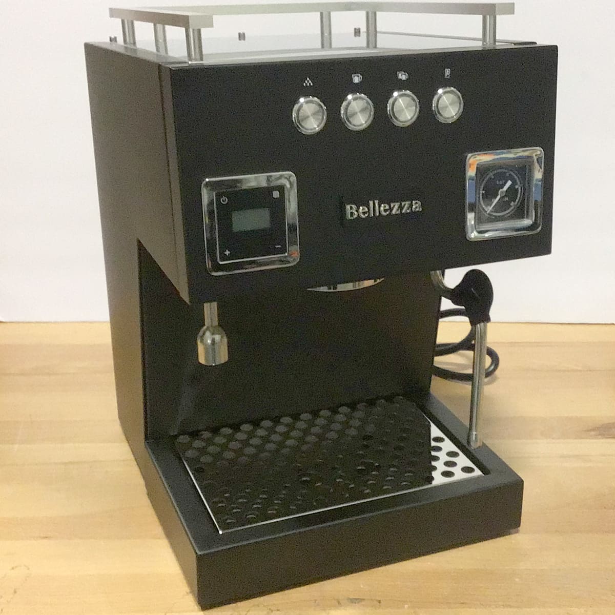 A black Bellezza espresso machine with control knobs, a steam wand, a pressure gauge, and a digital display sits on a wooden countertop against a plain background, ready for packing or brewing your next cup. © 2025 1st-line.com
