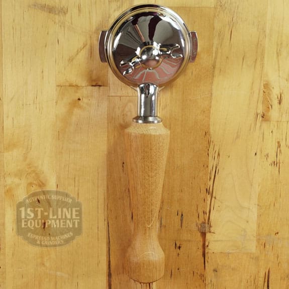 A LIKE NEW - Elektra Verve Dual Boiler Espresso Machine (C104) portafilter with a wooden handle rests on a light wood surface featuring a 1st-Line Equipment watermark, with the metal filter basket facing up and reflecting some light. © 2025 1st-line.com