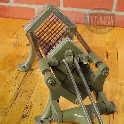 A SIDEWALK SALE - Halco French Fry Cutter Maker (E110) with a metal grid blade is mounted on wood, set against a brick wall background. © 2025 1st-line.com