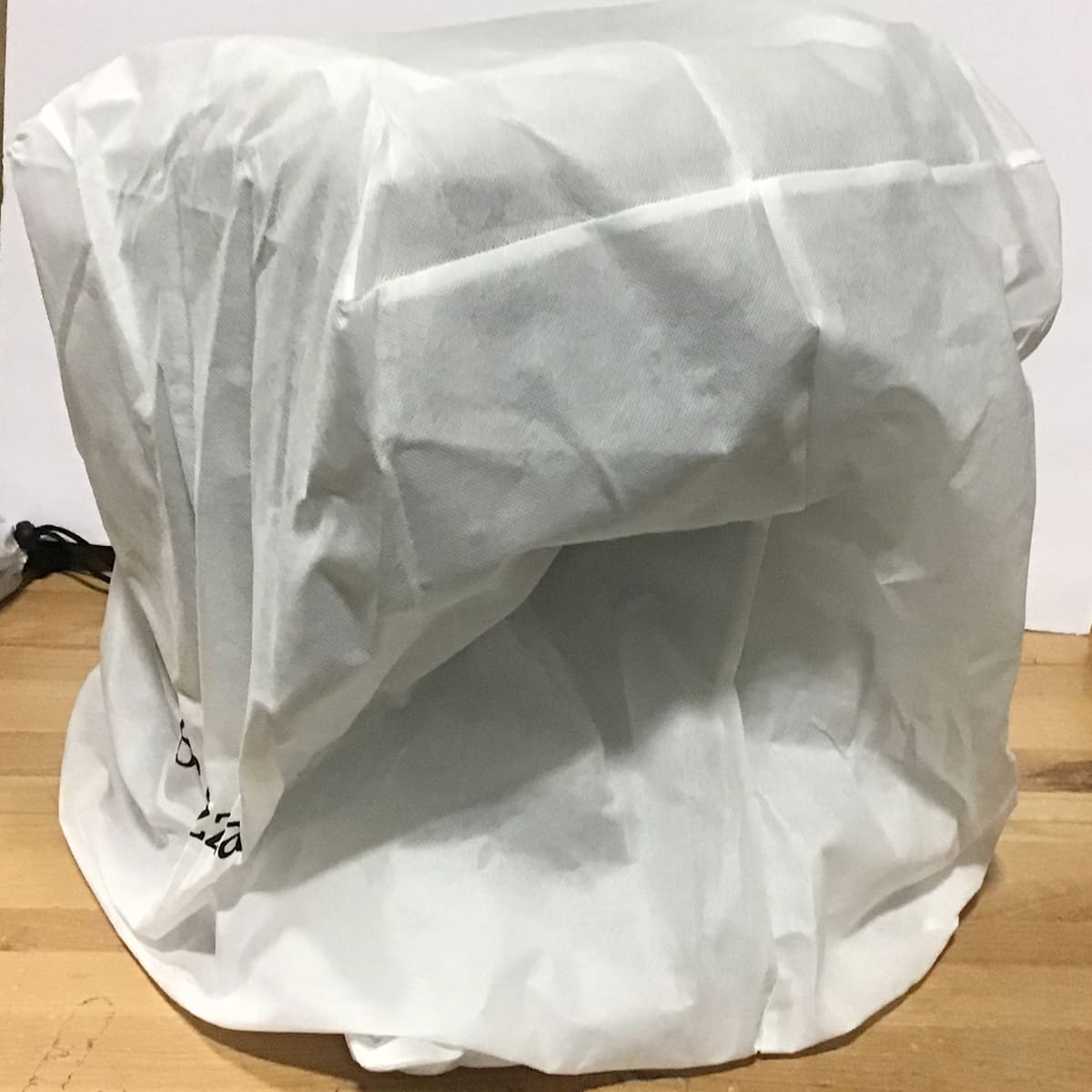 A small kitchen appliance, possibly a Bellona or Bellezza model, sits on a wooden surface, concealed beneath a white packing cloth. Only the outline of the appliance is visible under the fabric cover. © 2025 1st-line.com
